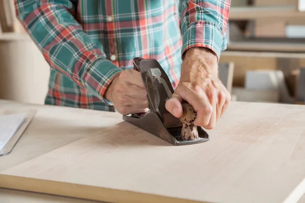 Falegname che utilizza pialla su legno in officina — Foto Stock