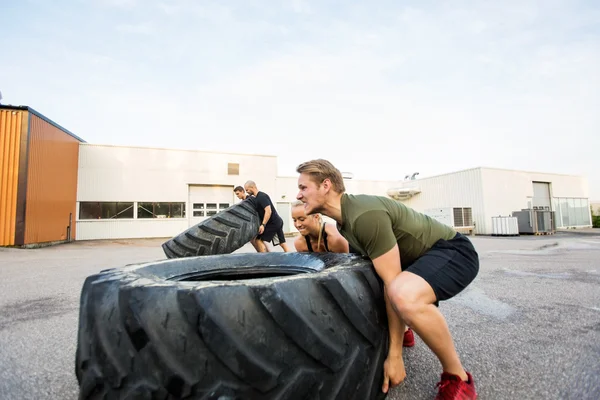 Ajuster les athlètes faisant un exercice de retournement de pneu — Photo