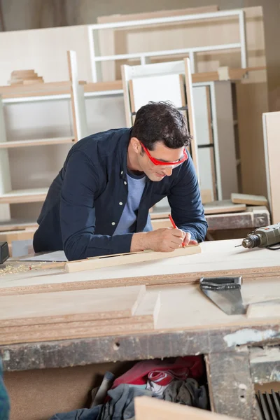 Carpentiere che misura il legno al banco da lavoro — Foto Stock