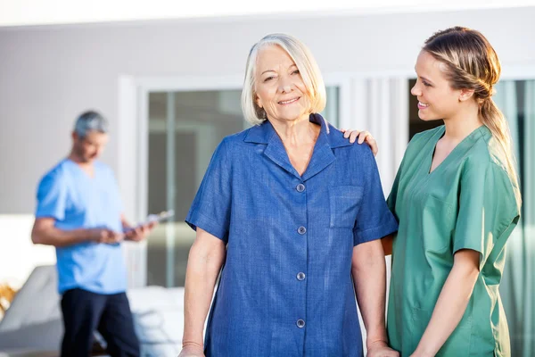 Senior Woman Being Assisted By Female Caretaker In Nursing Home — Stock Photo, Image