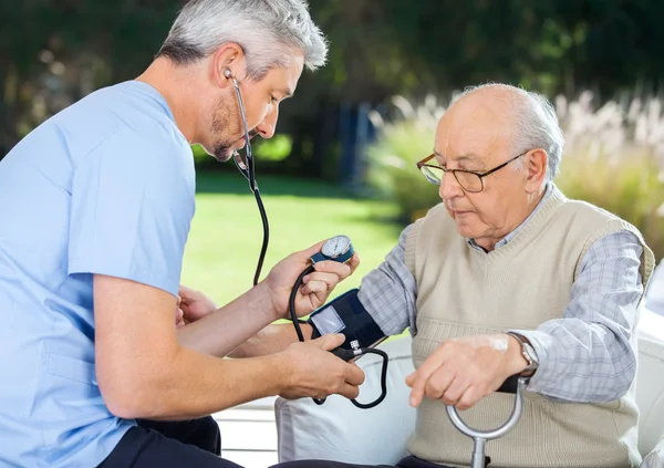 Medico che misura la pressione sanguigna dell'uomo anziano — Foto Stock