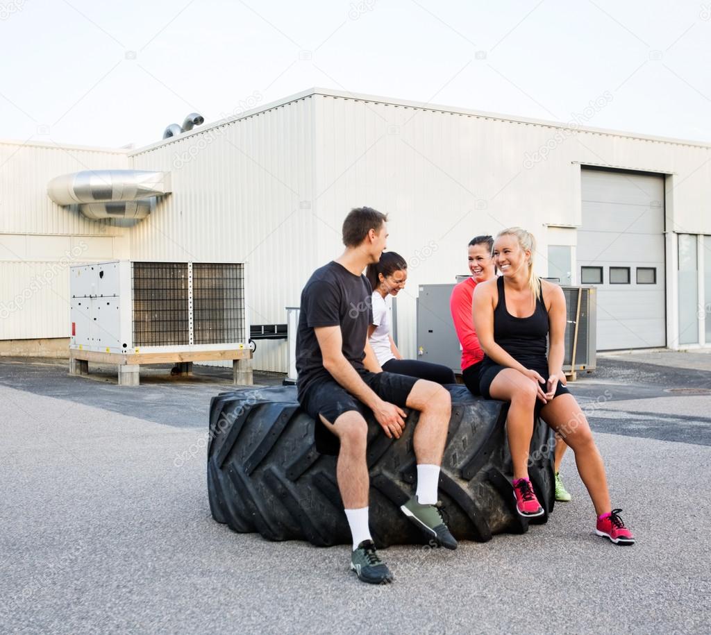 Fit Friends Conversing While Relaxing On Tire