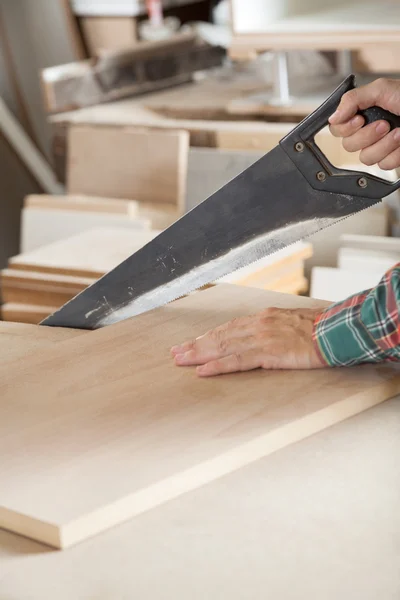 Immagine tagliata del falegname che taglia il legno con la sega a mano — Foto Stock