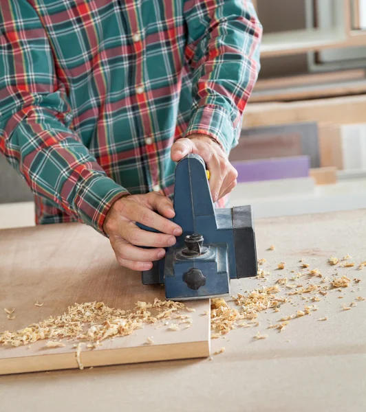 Midsection do carpinteiro que trabalha com plaina elétrica — Fotografia de Stock
