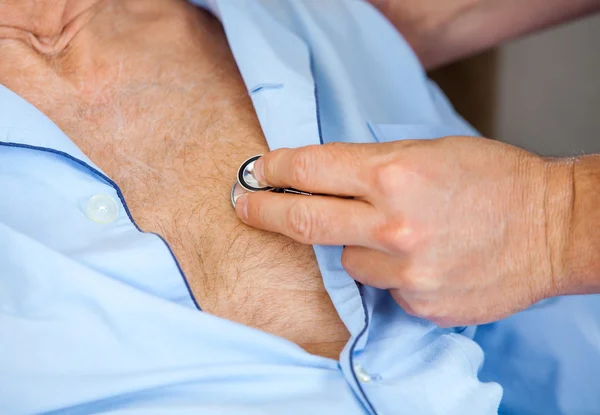 Cuidador examinando el pecho de los hombres mayores con estetoscopio — Foto de Stock