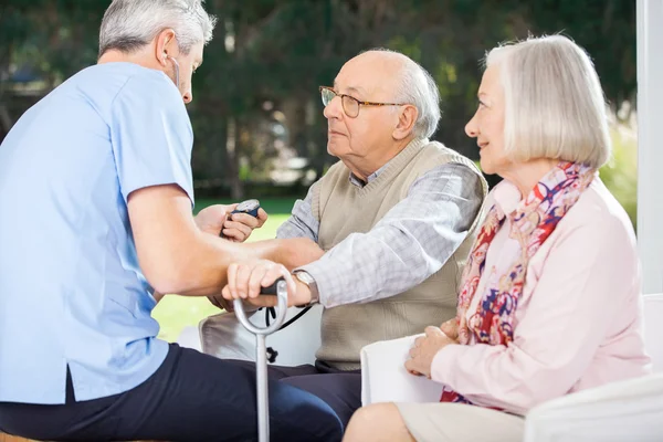 Mannelijke arts meten van de bloeddruk van Senior Man — Stockfoto