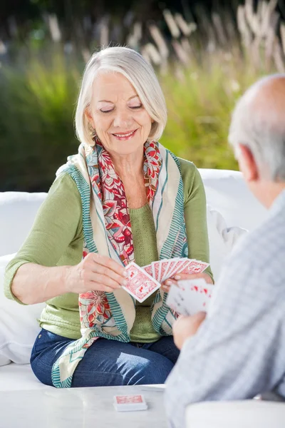 Glückliche Seniorin spielt Karten mit Mann — Stockfoto