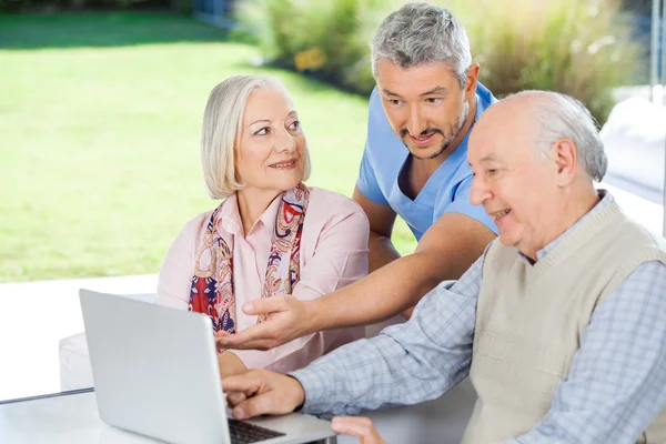 Male Caretaker Showing Something To Senior Couple On Laptop — Stock Photo, Image