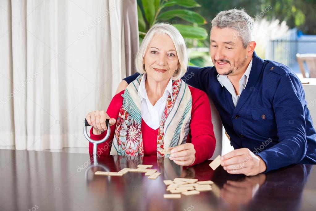 Grandmother Playing Dominoes With Grandson At Nursing Home