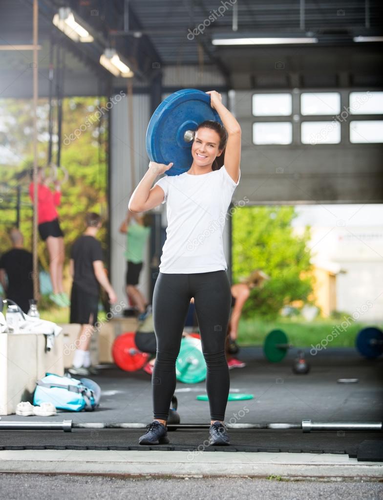 Portrait Of Woman Lifting Barbell Plate in Box