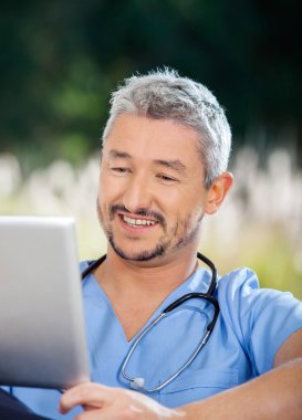 Tablet bilgisayarda bakarken gülümseyen erkek bekçi