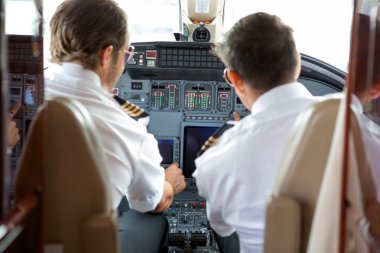 Pilots Operating Controls Of Corporate Jet clipart
