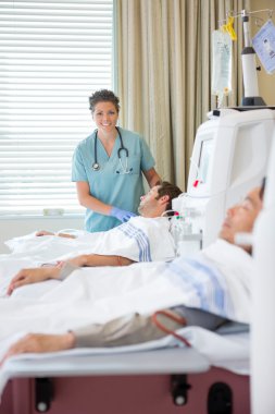 Nurse Standing By Patient Undergoing Renal Dialysis clipart