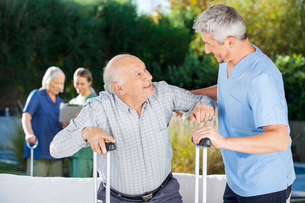 Male And Female Caretakers Helping Elderly People