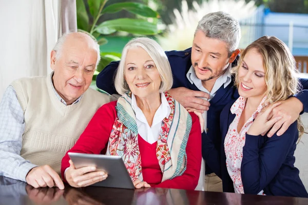 Femme âgée utilisant la tablette numérique avec la famille à la maison de soins infirmiers — Photo