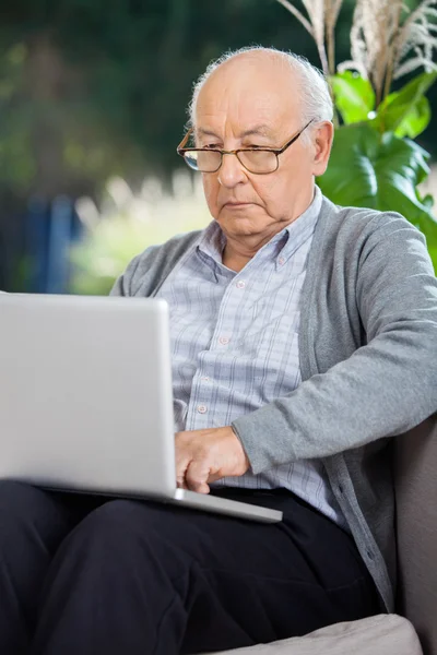 Starszy człowiek korzysta z laptopa na ganku — Zdjęcie stockowe