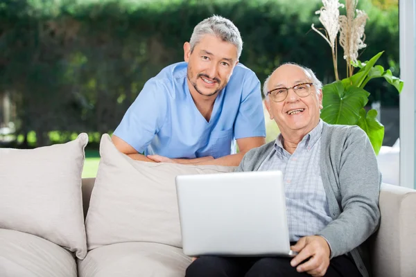 Fröhliche Krankenschwester und älterer Herr mit Laptop — Stockfoto