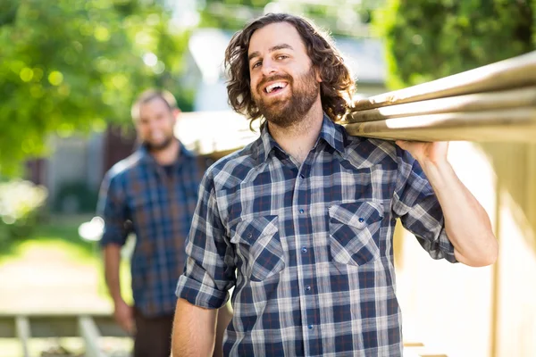 Timmerman met collega uitvoering planken terwijl lachen — Stockfoto