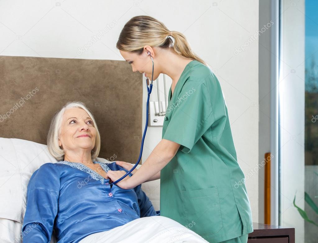Caretaker Examining Senior Woman At Nursing Home