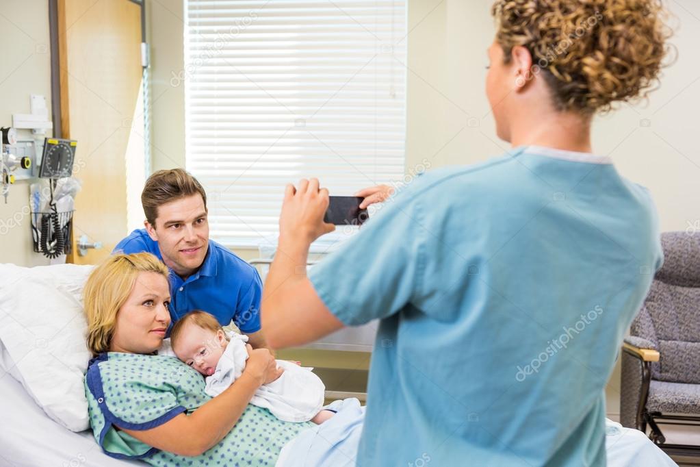 Nurse Photographing Couple With Newborn Baby Through Cellphone