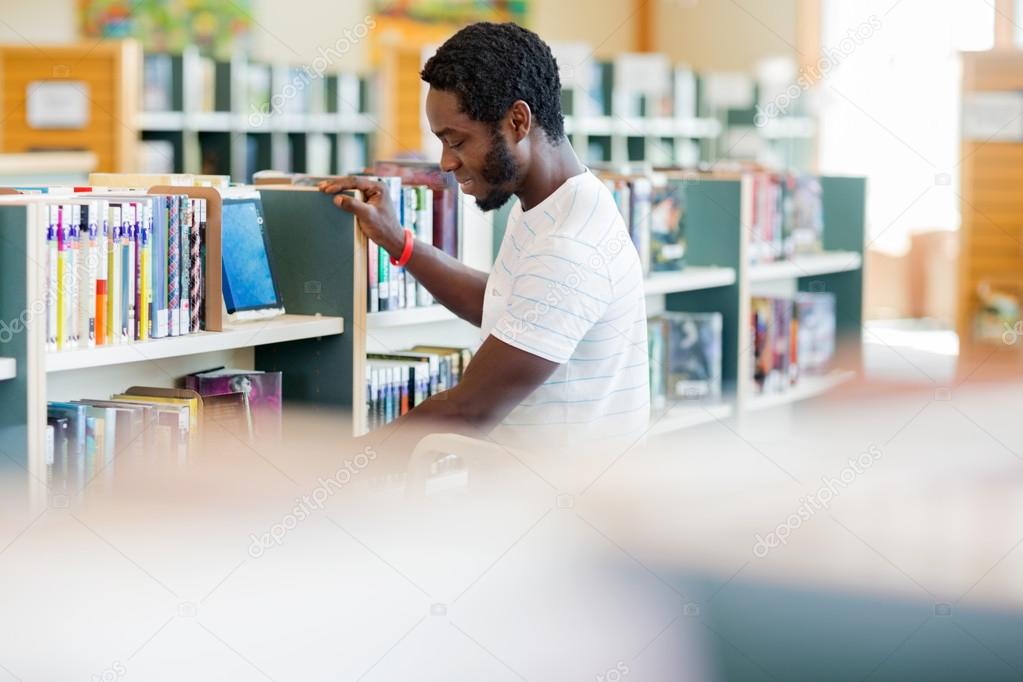 Male Librarian Arranging Books In Bookstore
