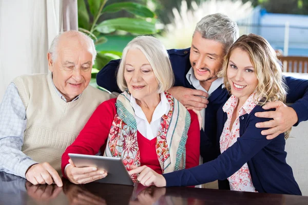 Женщина с помощью цифрового планшета с семьей в доме престарелых — стоковое фото
