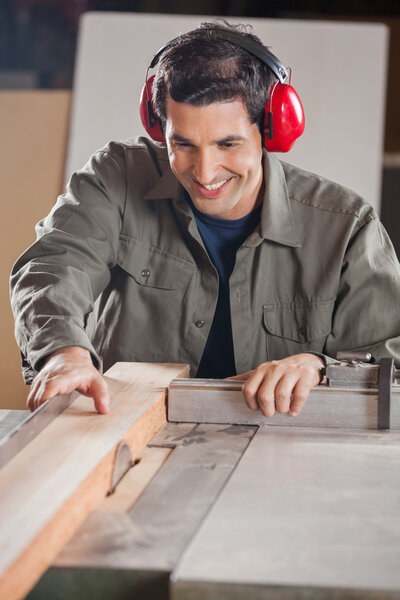 Happy Carpenter Cutting Wooden Plank With Tablesaw
