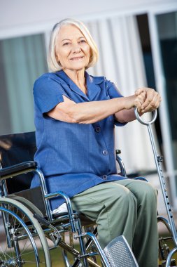 Bahçesinde tekerlekli sandalye üzerinde oturan gülümseyen kadın kıdemli