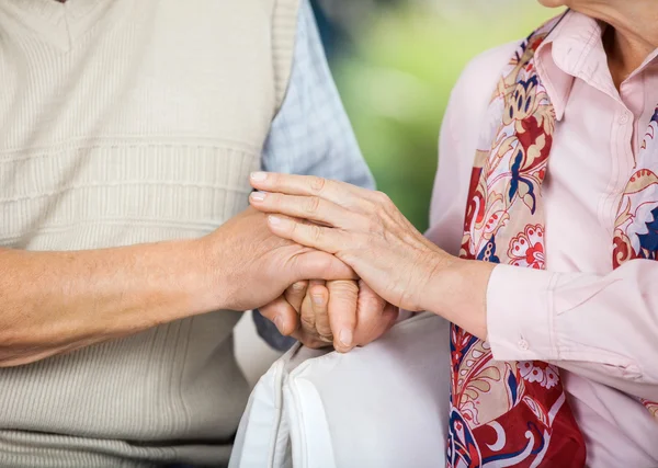 Seniorenpaar hält sich auf Stühlen an den Händen — Stockfoto