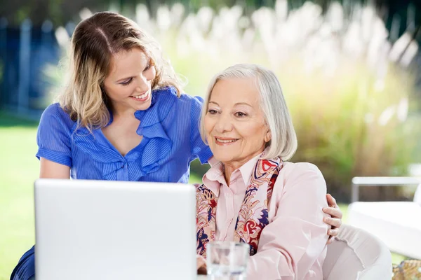 Glückliche Enkelin mit Seniorin mit Laptop auf Veranda — Stockfoto