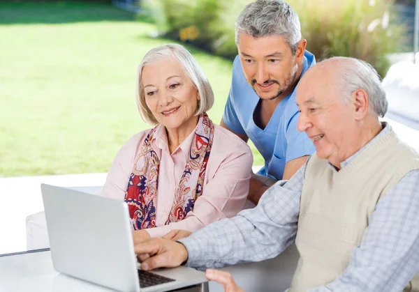 Custode Guardando Coppia anziana utilizzando il computer portatile — Foto Stock