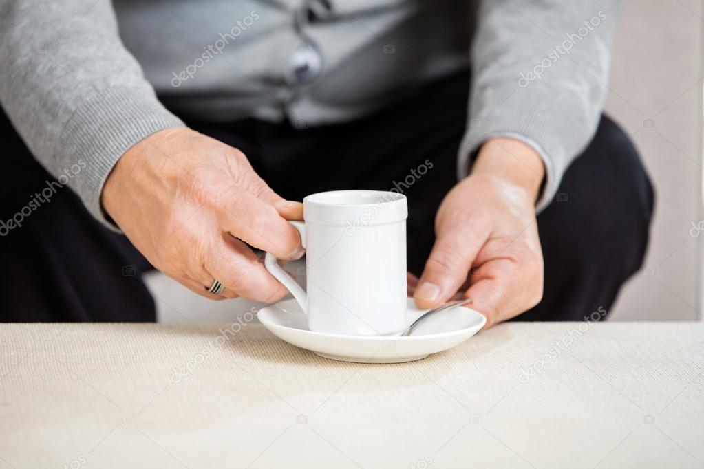 Midsection Of Senior Man Holding Coffee Cup