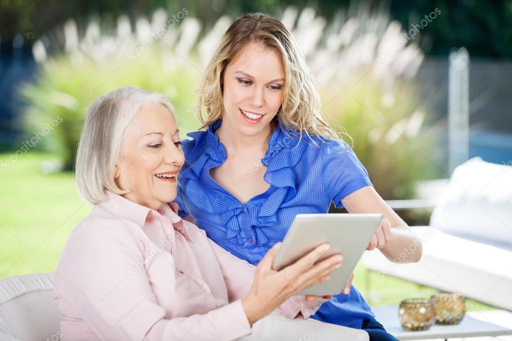 Happy Grandmother And Granddaughter Using Digital Tablet