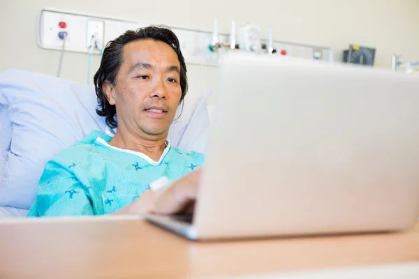 Patienten använder laptop på sjukhussäng — Stockfoto