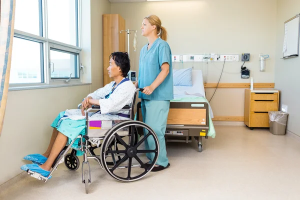 Enfermeira com paciente sentado na cadeira de rodas na janela do hospital — Fotografia de Stock