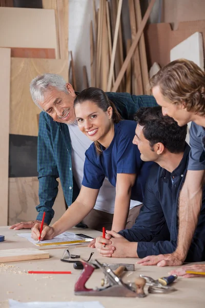 Vrouwelijke Carpenter werken met collega's In Workshop — Stockfoto