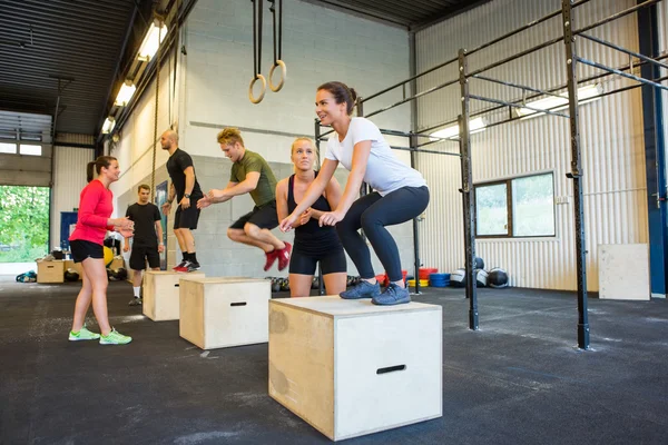 Sportovci dělají box jumps v tělocvičně — Stock fotografie