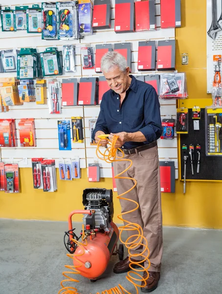 Старший человек рассматривает компрессор воздуха в магазине — стоковое фото