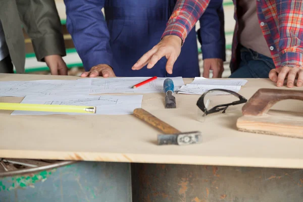 Carpintero explicando el plan a sus colegas en la mesa — Foto de Stock