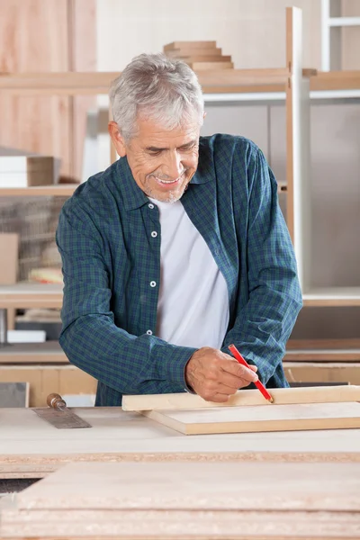 Senior-Schreiner markiert Holz mit Bleistift — Stockfoto