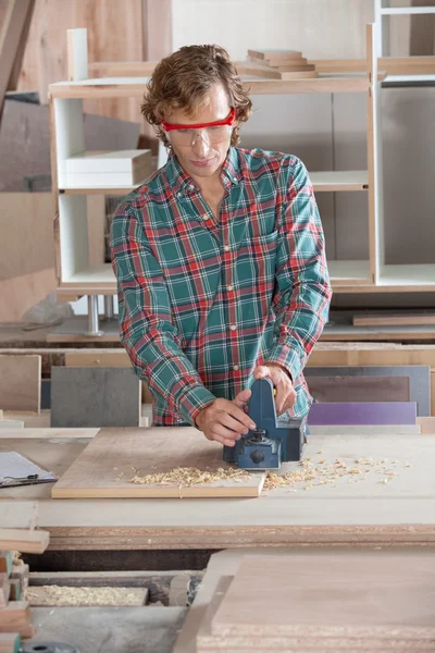 Schreiner mit Elektrohobel auf Holz — Stockfoto