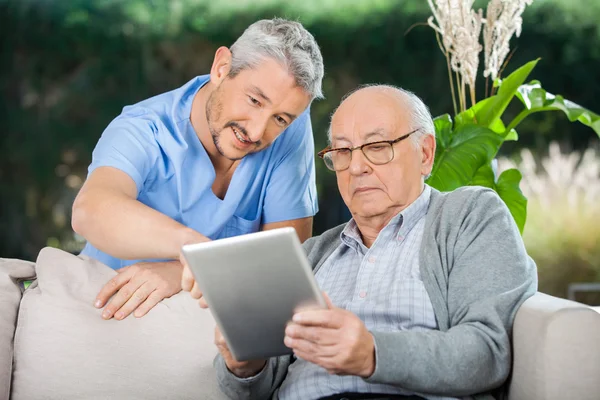 Gardien aidant l'homme âgé à utiliser une tablette numérique — Photo