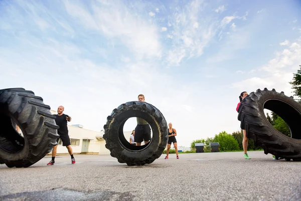Atleti che fanno esercizio di capovolgimento degli pneumatici — Foto Stock
