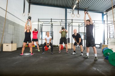 Fitness kutusu içinde Kettlebells kaldırma sporcular çapraz