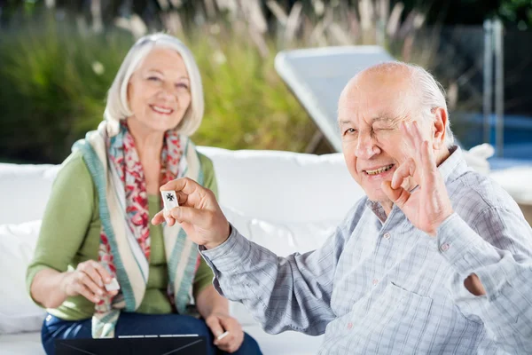 Senior gestikuliert okay, während er Rommé mit Frau spielt — Stockfoto