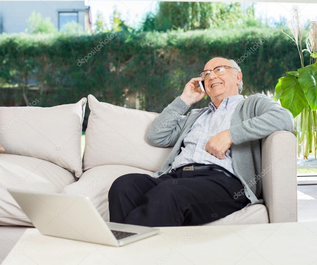 Relaxed Senior Man Using Mobilephone On Couch