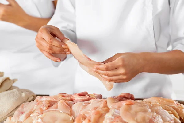 Carnicero sosteniendo pieza de pollo crudo en la carnicería — Foto de Stock