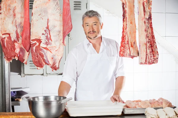 Metzger inmitten von Fleisch, das im Laden hängt — Stockfoto