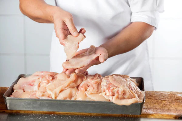 Carnicero sosteniendo trozos de pollo en el mostrador —  Fotos de Stock