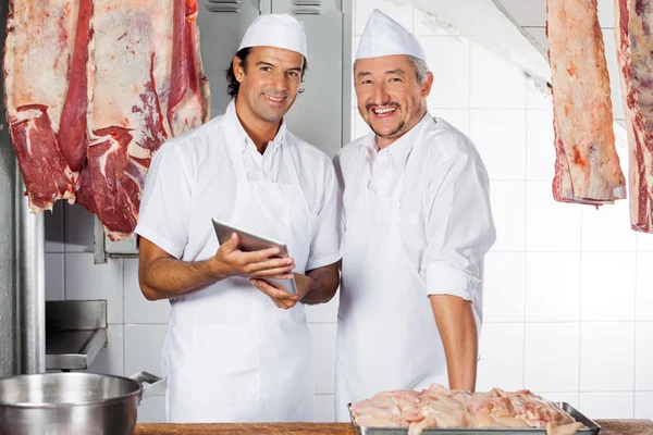 Carniceiros felizes com comprimido digital no balcão — Fotografia de Stock